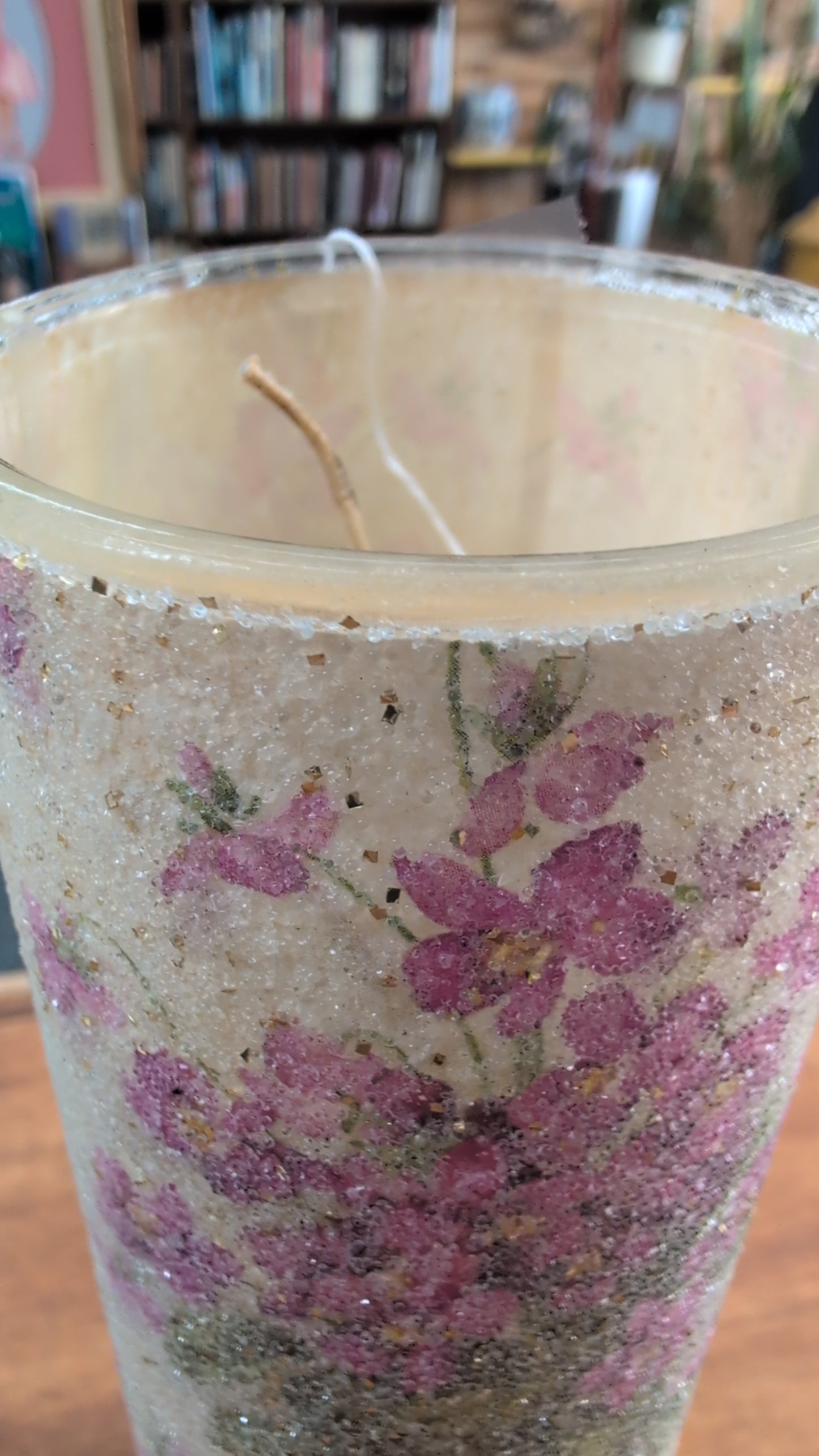 Decorative candle with floral and glitter design.