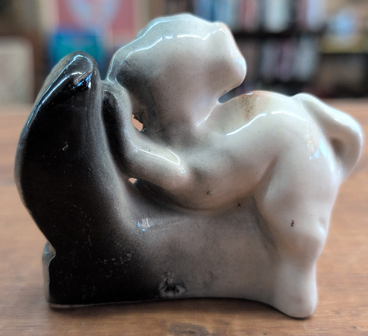 Ceramic dog figurine perched on a black boot. 3 inch tall