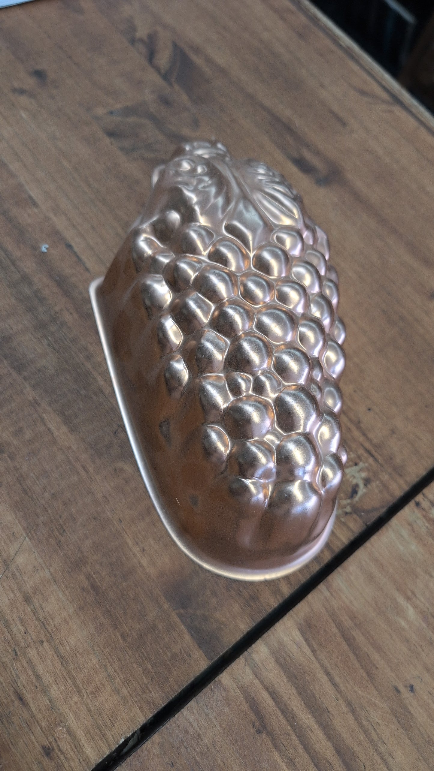 A vintage copper mold shaped like a cluster of grapes.