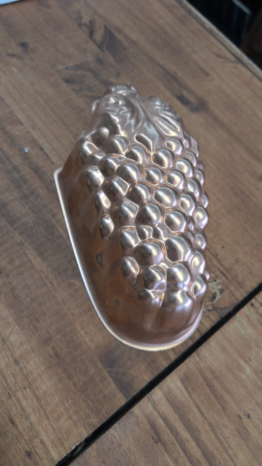 A vintage copper mold shaped like a cluster of grapes.