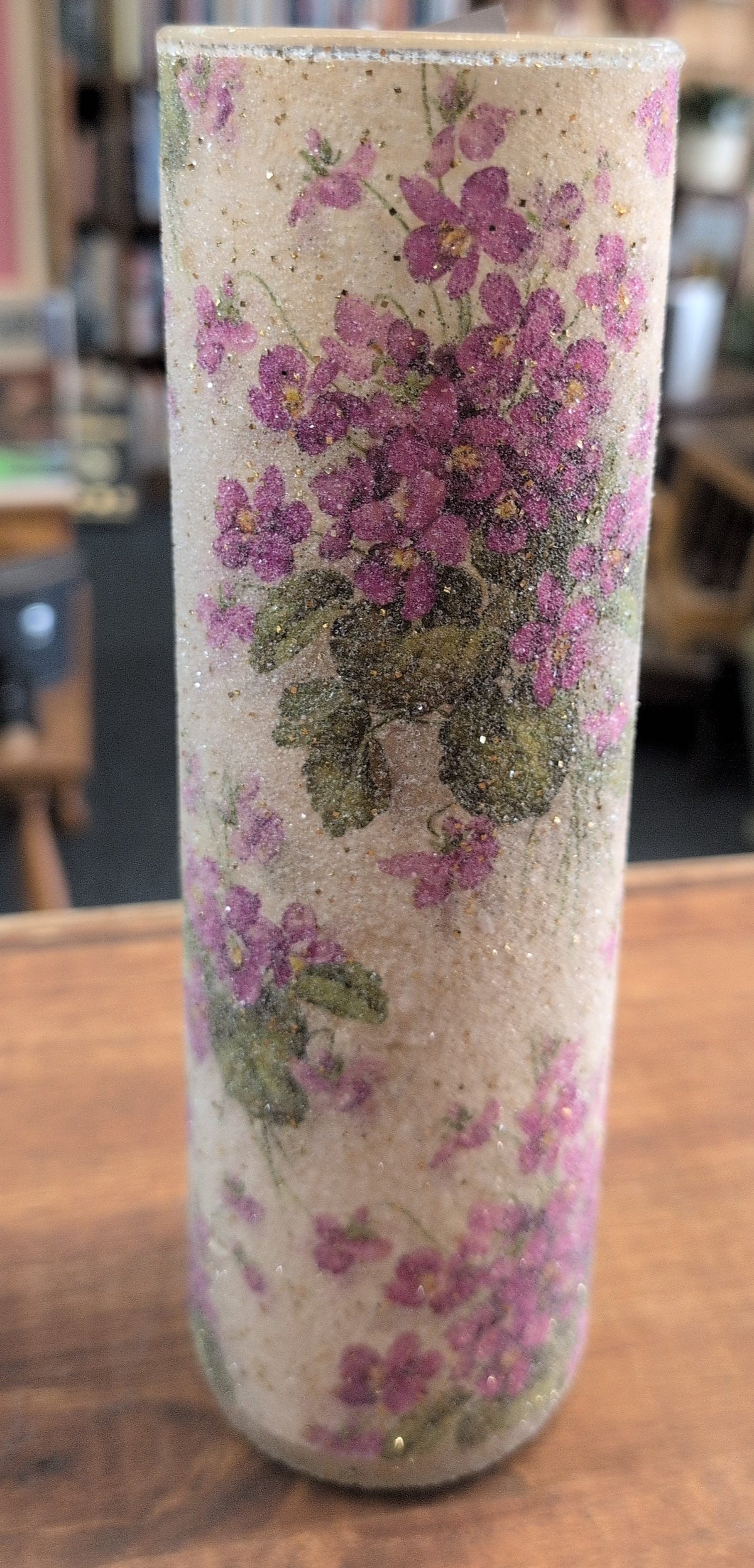Decorative candle with floral and glitter design.
